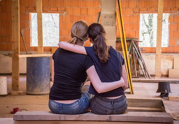 Two Girlfriends Sat Hugging