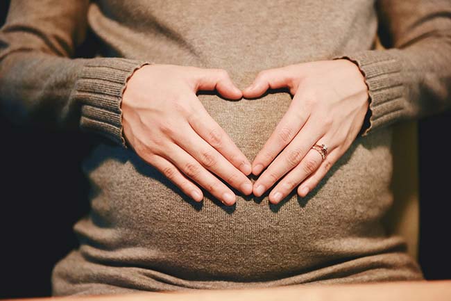 Hands in a Heart Shape on Pregnancy Bump