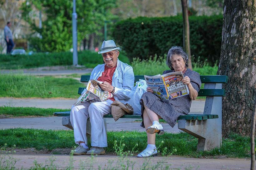 Old Couple Reading Papers on a Bench