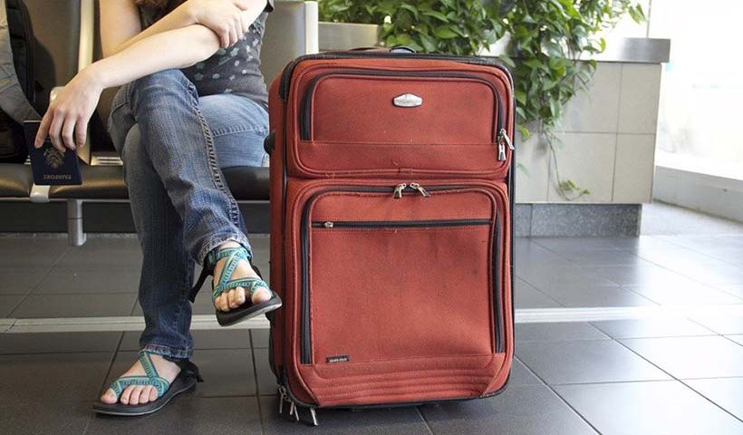 Girl Sat at Airport Gate with Suitcase