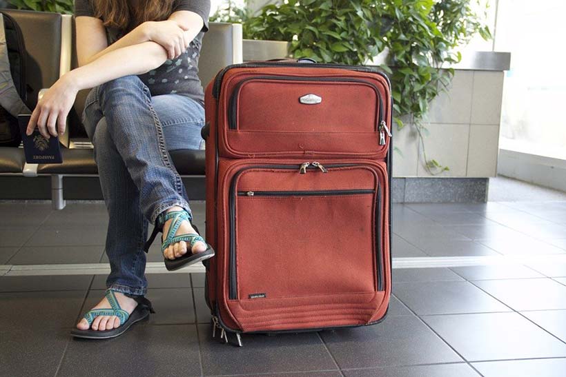 Girl Sat at Airport Gate with Suitcase